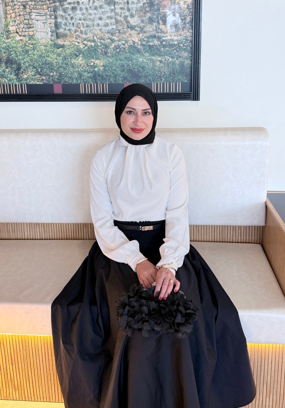 Huda Altamimi, founder of EmpowerHer Voices, seated and smiling